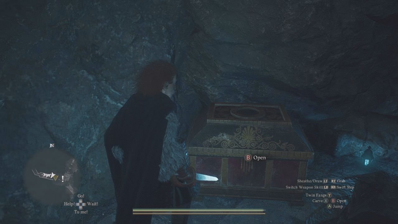 With a dagger drawn, the player approaches a red treasure chest in a cave.