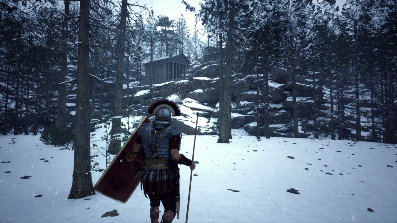 A soldier stands in a snowy clearing, looking up a rugged trail toward some stone buildings on a hill.