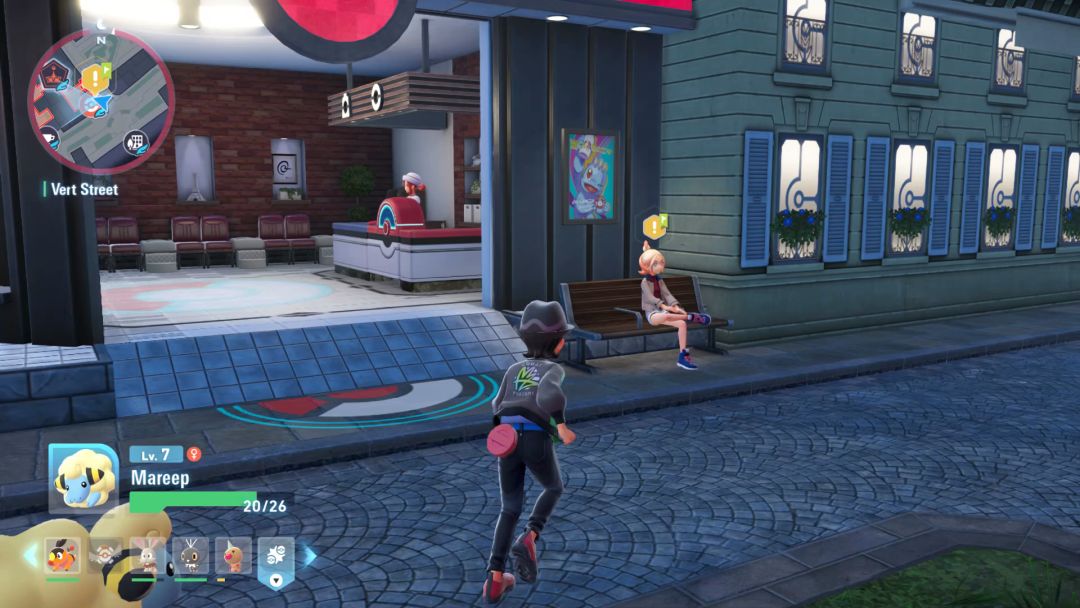 Taunie is seated on a bench outside the Vert Pokemon Center, with the sales counter visible through an opening to her right.