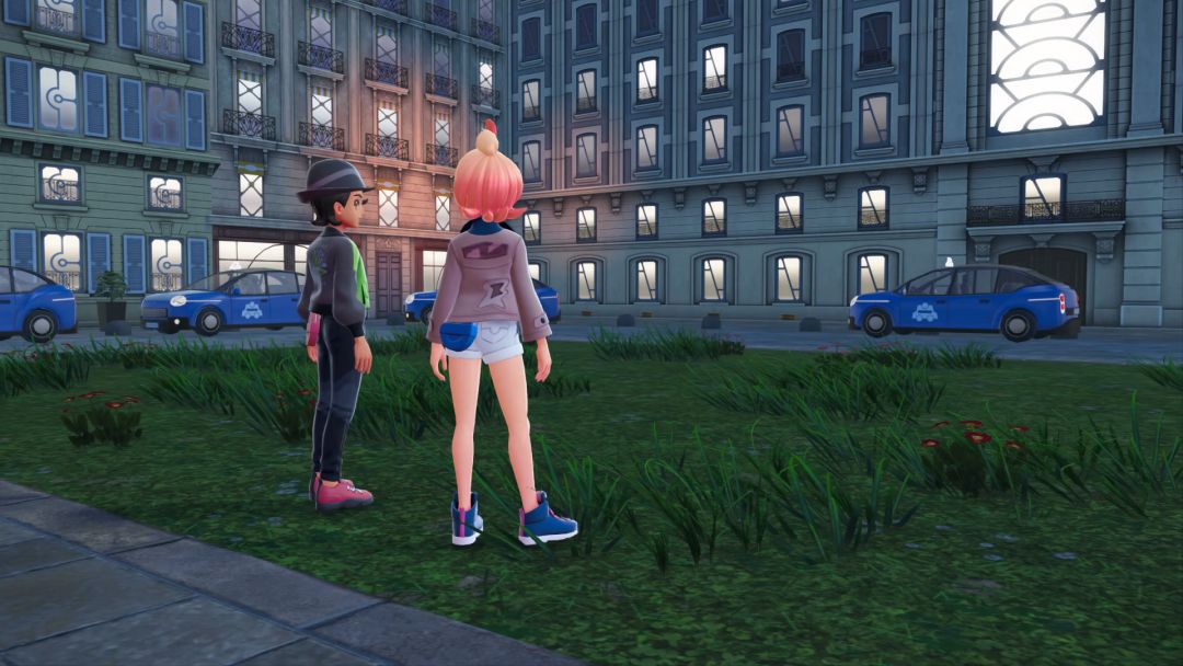 The Pokemon Trainer and Taunie stand on a patch of grass, looking toward a parking lot and a blue car ahead of a gray stone building.